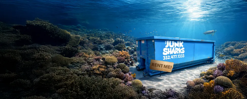 A blue Junk Sharks roll-off dumpster on a coral reef with a Rent Me sign